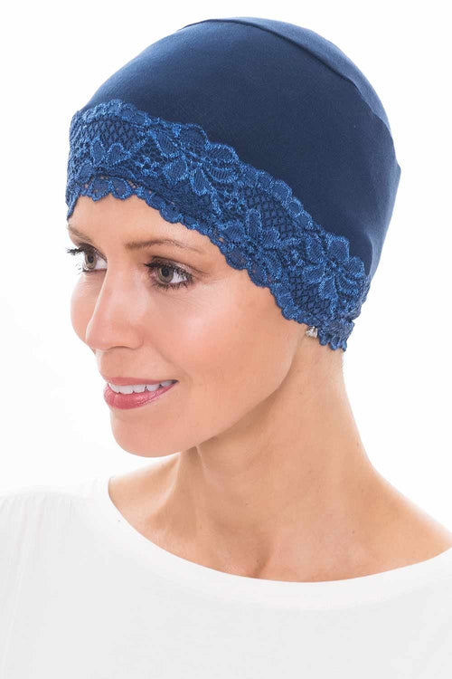 Woman in navy blue lace trimmed sleep cap in beanie style for women with cancer