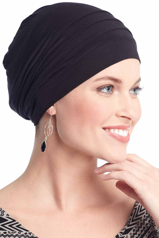 Woman in black chemo hat in turban style with pleats