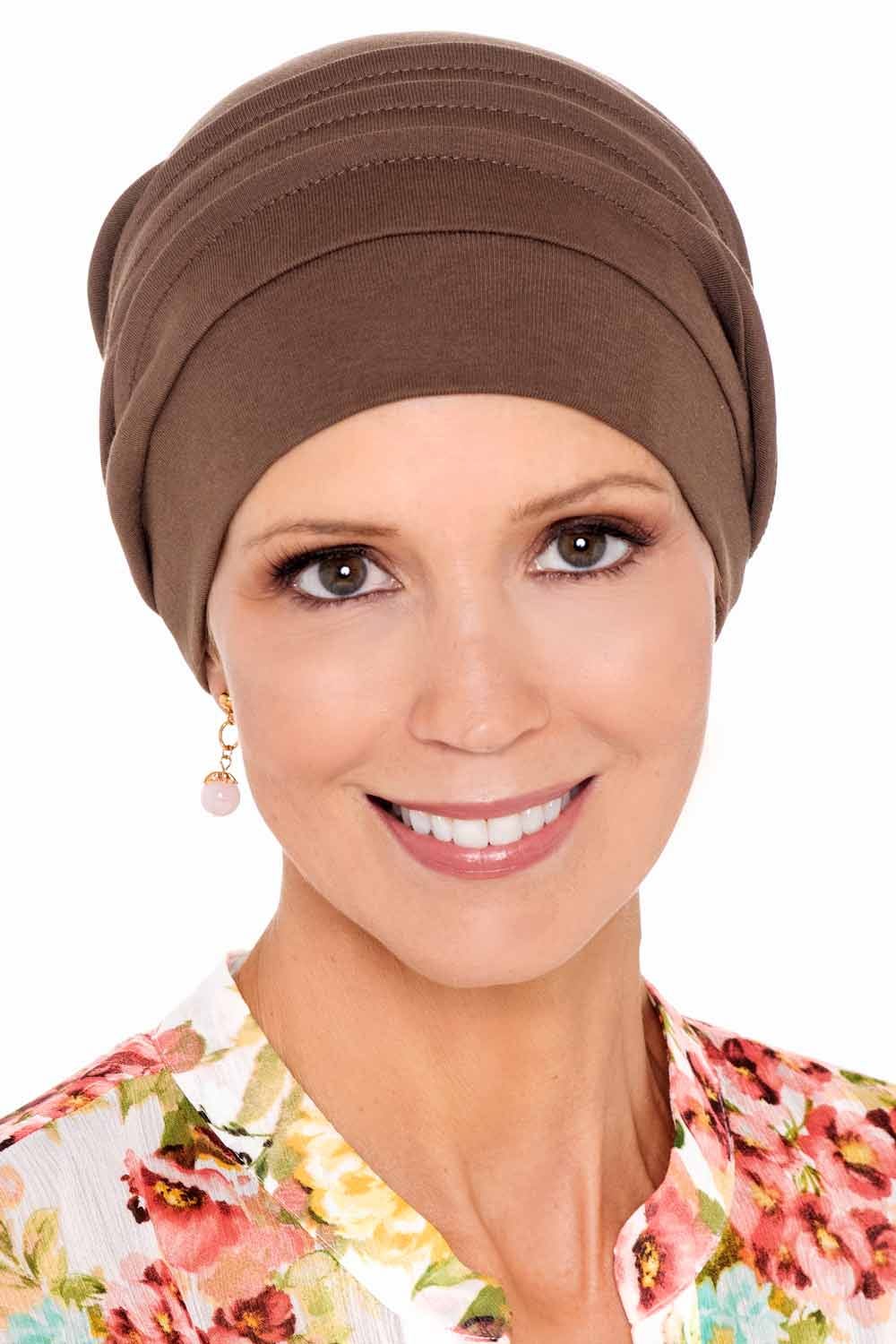 Woman in flowered shirt wearing brown chemo hat with pleats