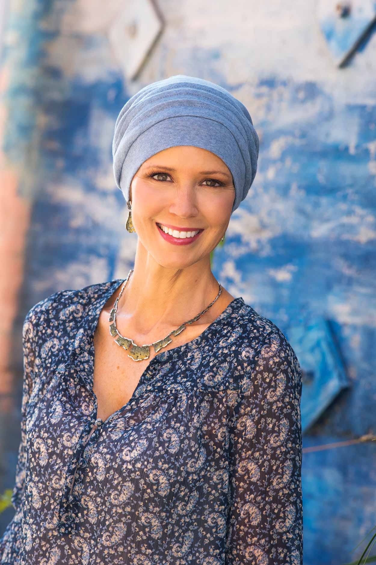 Woman outdoors with blue background wearing blue pleated cotton chemo hat